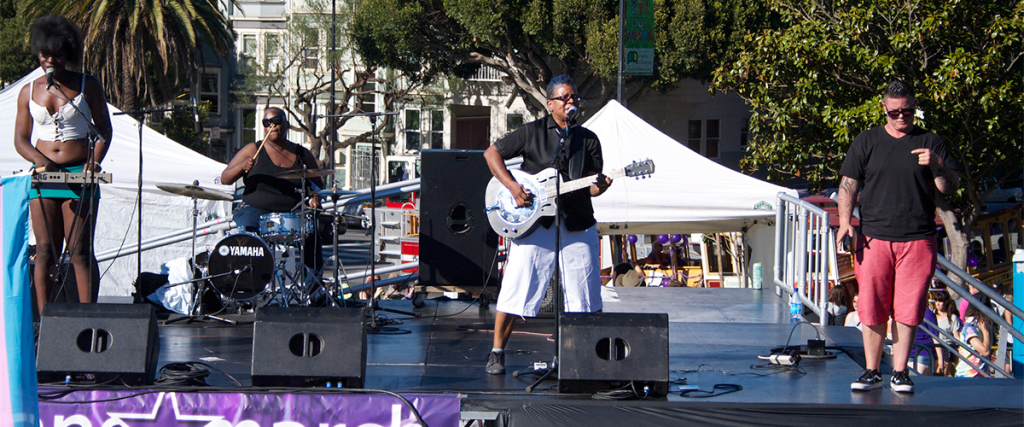 3 musicians and an ASL interpreter on the Trans March stage.